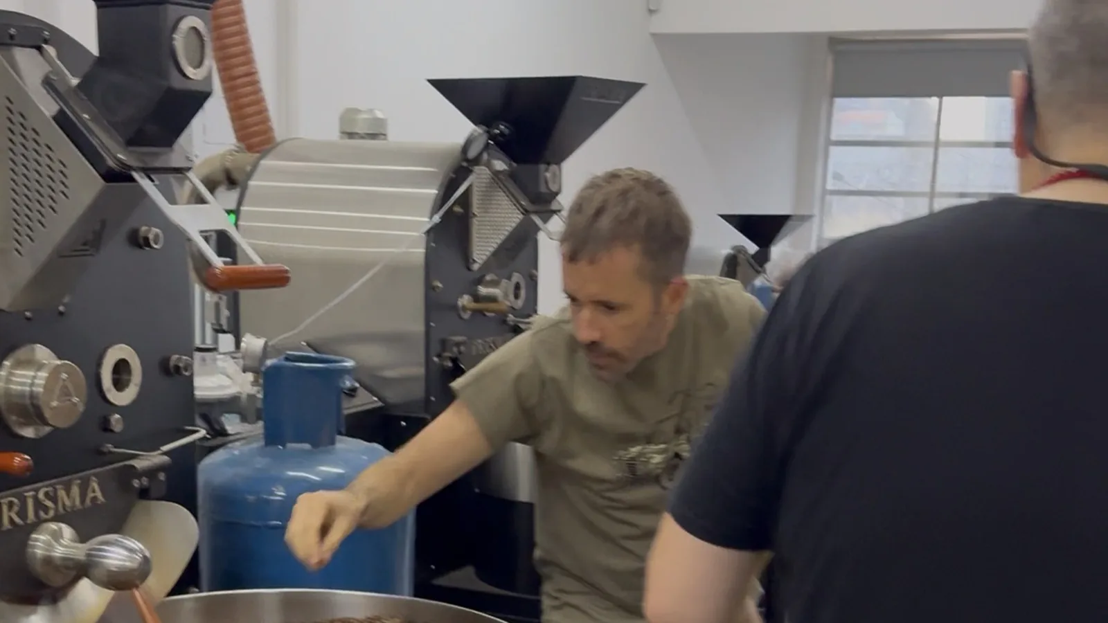 Andrea Onelli mete la mano en la bandeja de enfriamiento llena de café recién tostado.